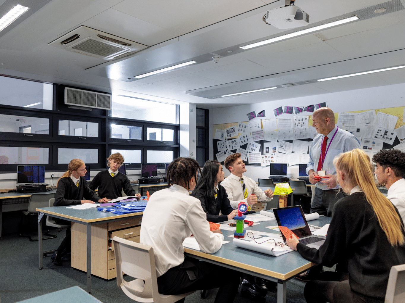 A classroom with several students listening to their teacher.